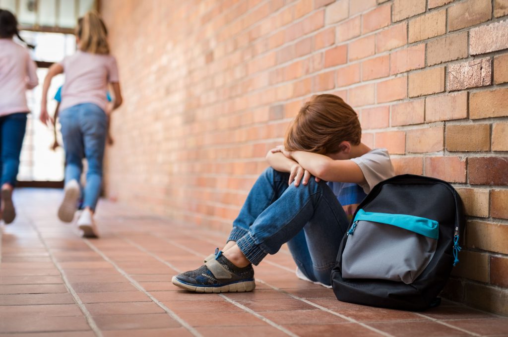 Schulkind sitzt am Boden